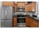 Modern kitchen showcasing stainless steel appliances, including a refrigerator, oven, and microwave, with wood cabinetry at 4528 W Valencia Dr, Laveen, AZ 85339