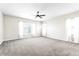 Spacious carpeted bedroom featuring a ceiling fan and natural light from two large windows at 4926 S Hemet St, Gilbert, AZ 85298