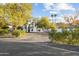 Beautiful white home with a brick driveway and lush desert landscaping, offering a welcoming curb appeal at 5601 E Caballo Dr, Paradise Valley, AZ 85253