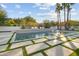 Modern swimming pool area with palm trees, lounge chairs, and stepped stone pavers surrounded by green grass at 5601 E Caballo Dr, Paradise Valley, AZ 85253