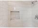 Updated shower featuring light tile work, a built in shower caddy, and modern fixtures at 6808 N 33Rd Ave, Phoenix, AZ 85017