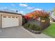 Charming home exterior featuring a white garage door, gray brick wall with vibrant red bougainvillea, and manicured lawn at 7334 N 7Th Ave, Phoenix, AZ 85021