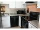 Kitchen features white cabinets, black appliances, and granite countertops at 8649 E Royal Palm Rd # 213, Scottsdale, AZ 85258