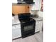 Galley kitchen features a black range and oven appliance against white cabinets and light countertops at 8649 E Royal Palm Rd # 213, Scottsdale, AZ 85258