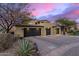 An exterior elevation of the home with three garages and stone accents along the facade at 10638 E Hedgehog Pl, Scottsdale, AZ 85262
