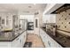 Galley kitchen featuring granite counters, white cabinets, tile backsplash, and stainless steel appliances at 1152 W Horseshoe Ave, Gilbert, AZ 85233