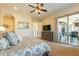 Bright main bedroom with a door to the covered patio, dresser with TV and a ceiling fan at 1488 E Sweet Citrus Dr, Queen Creek, AZ 85140