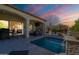 Outdoor pool with water feature, covered patio, and a fireplace under a colorful sky at 1488 E Sweet Citrus Dr, Queen Creek, AZ 85140