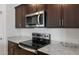 Close-up of modern stainless steel appliances, granite countertops, and dark wood cabinets in the kitchen at 16505 N Comet Trl, Maricopa, AZ 85138