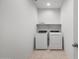 A small laundry room with white washer and dryer machines and a shelf at 16505 N Comet Trl, Maricopa, AZ 85138