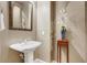 Elegant powder room with a pedestal sink, decorative mirror, and ornate accent table at 17991 N 95Th St, Scottsdale, AZ 85255