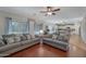 Open-concept living room with hardwood floors, grey sofas and an open view into the kitchen and dining area at 21613 N Sunset Dr, Maricopa, AZ 85139