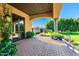 Covered patio with stone floors and doorway to landscaped backyard with mature trees at 21962 E Diana Way, Queen Creek, AZ 85142