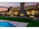 An amazing property featuring an outdoor fireplace and dining area, with lush green grass and sunset backdrop at 21962 E Diana Way, Queen Creek, AZ 85142