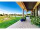 Beautiful backyard with large lawn, pool, and covered patio with stone columns at 21962 E Diana Way, Queen Creek, AZ 85142