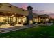 An amazing property featuring an outdoor fireplace and dining area, with lush green grass and sunset backdrop at 21962 E Diana Way, Queen Creek, AZ 85142