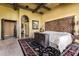 Comfortable bedroom with a dark rug, exposed beams, and a unique headboard design at 21962 E Diana Way, Queen Creek, AZ 85142