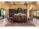 Open dining area with a large table, dark cabinetry, travertine flooring, and decorative chandeliers at 21962 E Diana Way, Queen Creek, AZ 85142