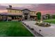Grand two-story home with stone accents, manicured lawn, fountain and patterned brick driveway at dusk at 21962 E Diana Way, Queen Creek, AZ 85142