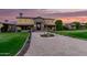 Grand two-story home with stone accents, manicured lawn, fountain and patterned brick driveway at dusk at 21962 E Diana Way, Queen Creek, AZ 85142