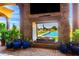 Outdoor living area featuring a stone fireplace, comfortable seating, and a view of the sparkling pool and lush greenery at 21962 E Diana Way, Queen Creek, AZ 85142
