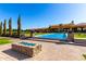Beautiful outdoor space featuring a sparkling pool with fountains, a brick patio, and a blue glass fire pit at 21962 E Diana Way, Queen Creek, AZ 85142