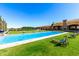 Expansive backyard featuring a large, sparkling pool, lush green lawn, and comfortable lounge chairs for relaxation at 21962 E Diana Way, Queen Creek, AZ 85142