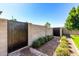 Landscaped side yard featuring a decorative metal gate, paved pathway, and lush green shrubs at 21962 E Diana Way, Queen Creek, AZ 85142