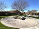 Community fire pit on a brick surface with mature trees, built-in benches, and green grass at 236 N Wesley --, Mesa, AZ 85207