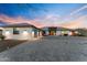 Desert home's front exterior features a stone driveway and xeriscaping, bathed in the warm glow of sunset at 2500 Lupine Ln, Wickenburg, AZ 85390