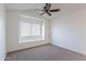 A well lit bedroom with neutral carpet, window, and a ceiling fan at 433 E Utopia Rd, Phoenix, AZ 85024