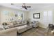 Bright living room with neutral color palette, plush seating, ceiling fan, and window shutters at 44196 W Askew Dr, Maricopa, AZ 85138