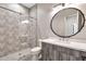 Stylish bathroom with mosaic tile shower, glass door, round mirror, and a gray vanity at 8730 E Tether Trl, Scottsdale, AZ 85255