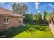 Lush backyard with green artificial turf, mature trees, a neutral-colored house, and a beautiful blue sky at 10490 E Dreyfus E Ave, Scottsdale, AZ 85260
