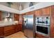 A modern kitchen boasts stainless steel appliances, including a refrigerator and wall oven, with cherry wood cabinetry at 10490 E Dreyfus E Ave, Scottsdale, AZ 85260