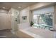 Bright main bathroom with a glass shower, soaking tub, and view to the exterior at 10490 E Dreyfus E Ave, Scottsdale, AZ 85260