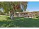 Lush backyard featuring a well-maintained lawn, mature trees, and a covered patio at 11011 N Coggins Dr, Sun City, AZ 85351