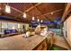Covered outdoor bar area with a built-in grill, bar stools, pendant lighting, and lush landscaping at 11801 N Sundown Dr, Scottsdale, AZ 85260