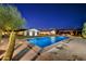 Stunning pool with water features, surrounded by desert landscaping, and a beautifully lit home in the background at 11801 N Sundown Dr, Scottsdale, AZ 85260