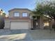 Two-story home featuring a two-car garage, desert landscaping, and a tree in the front yard at 12733 W Boca Raton Rd, El Mirage, AZ 85335