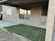 A view of the house's covered patio, including turf and an entrance to the home at 12733 W Boca Raton Rd, El Mirage, AZ 85335