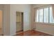 Bedroom with hardwood floors, closet, and window with plantation shutters and neutral curtains at 13417 W La Vina Dr, Sun City West, AZ 85375