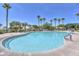 Spacious community pool featuring palm trees, shade structures, and lounge chairs at 17131 W Oberlin Way, Surprise, AZ 85387
