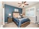 Stylish bedroom featuring a blue accent wall, ceiling fan, and a large window with shutters at 18637 E Flintlock Dr, Queen Creek, AZ 85142