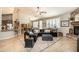 Open-concept living room featuring a stone fireplace, black leather sectional, and shuttered windows at 18637 E Flintlock Dr, Queen Creek, AZ 85142