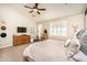 Bright main bedroom featuring a ceiling fan, a dresser with a TV, and neutral colored walls at 18637 E Flintlock Dr, Queen Creek, AZ 85142