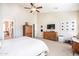 Bright main bedroom featuring a ceiling fan, a dresser with a TV, and neutral colored walls at 18637 E Flintlock Dr, Queen Creek, AZ 85142