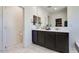 Bathroom showcasing dual sinks, dark cabinets, and tile floors, offering style and convenience at 21407 W Hubbell St, Buckeye, AZ 85396