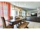Bright dining room features a wood table, bench, and a modern chandelier with orange curtains at 21407 W Hubbell St, Buckeye, AZ 85396