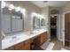 Bathroom showcasing double sinks with granite counters, decor, and an open doorway to the bedroom at 21857 N Gibson Dr, Maricopa, AZ 85139